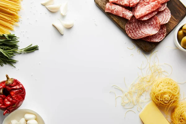 Vue du dessus du plateau de viande, des pâtes et des ingrédients sur fond blanc — Photo de stock