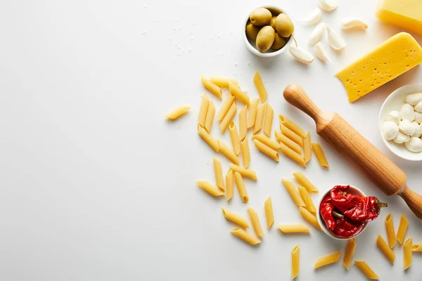 Vue du dessus des pâtes et rouleau à pâtisserie avec des ingrédients sur fond blanc — Photo de stock