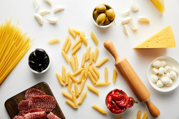 Vue du dessus du plateau de viande, du rouleau à pâtisserie, des pâtes et des ingrédients sur fond blanc — Photo de stock