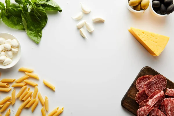 Top view of pasta, meat platter, cheese and ingredients on white background — Stock Photo