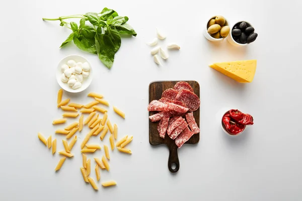 Vista dall'alto di pasta, piatto di carne, formaggio e ingredienti su bianco — Foto stock