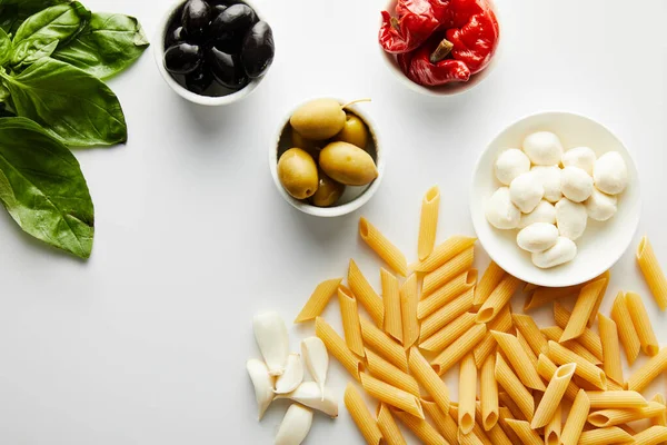 Vue du dessus des pâtes avec des ingrédients sur fond blanc — Photo de stock