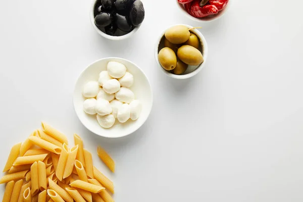 Top view of pasta and bowls with ingredients on white background — Stock Photo