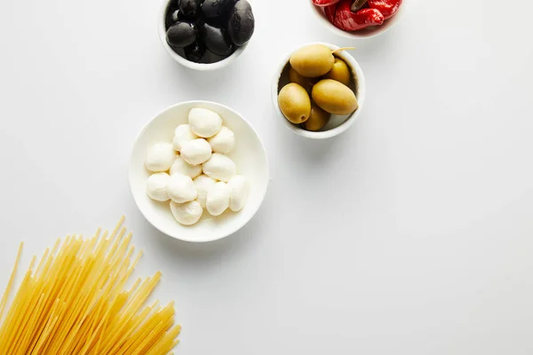 Vista dall'alto di spaghetti e ciotole con ingredienti su sfondo bianco — Foto stock