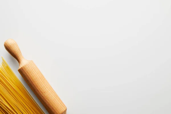 Top view of spaghetti and rolling pin on white background — Stock Photo