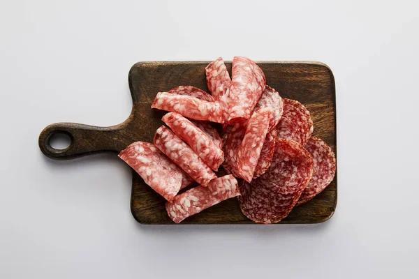 Top view of salami slices on board on white background — Stock Photo