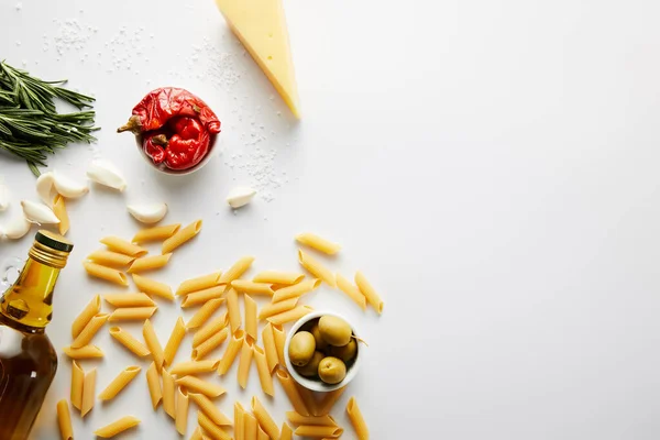 Vue du dessus de la bouteille d'huile d'olive, pâtes, fromage et ingrédients sur fond blanc — Photo de stock