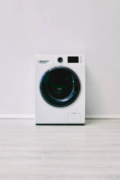 Machine à laver moderne sur le sol près du mur blanc dans la salle de bain — Photo de stock