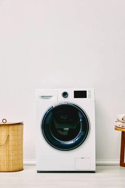 Modern washing machine near laundry basket in bathroom — Stock Photo