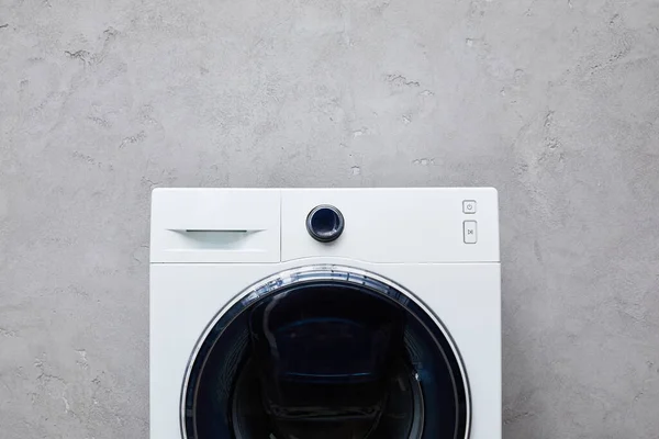 Weiße Waschmaschine in der Nähe der grauen strukturierten Wand im Badezimmer — Stockfoto