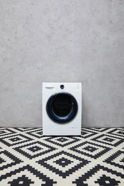 Modern washing machine near grey wall and ornamental carpet in bathroom — Stock Photo