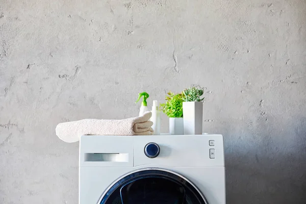 Plantas, toalhas e garrafas na máquina de lavar roupa no banheiro — Fotografia de Stock