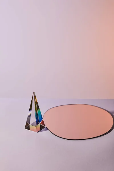 Kristall transparente Pyramide und runder Spiegel auf violettem Hintergrund — Stockfoto