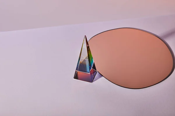 Cristal pyramide transparente et miroir rond sur fond violet — Photo de stock