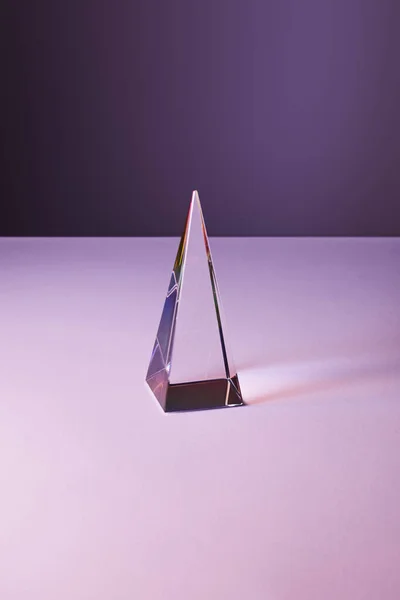 Pyramide transparente cristal avec réflexion de la lumière sur fond violet et violet — Photo de stock