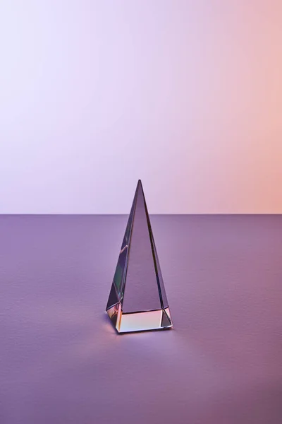 Crystal transparent pyramid with light reflection on violet and purple background — Stock Photo