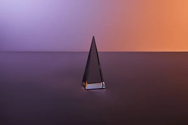 Pyramide transparente cristal avec réflexion de la lumière sur fond violet foncé — Photo de stock