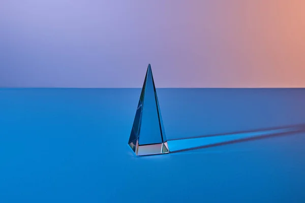 Kristall transparente Pyramide mit Lichtreflexion auf blauem Hintergrund — Stockfoto