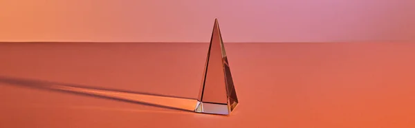 Crystal transparent pyramid with light reflection on orange background, horizontal crop — Stock Photo