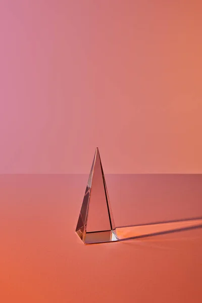 Pirámide transparente de cristal con reflejo de luz sobre fondo naranja - foto de stock