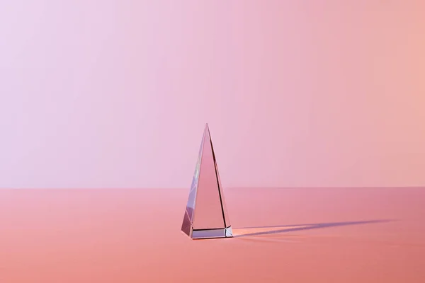 Pirámide transparente de cristal con reflexión sobre fondo rosa - foto de stock