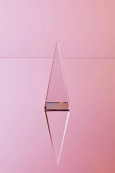 Кристалічна прозора піраміда з відображенням на рожевому фоні — стокове фото