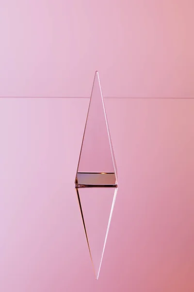 Crystal transparent pyramid with reflection on pink background — Stock Photo