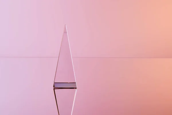 Pirâmide transparente de cristal com reflexão sobre fundo rosa — Fotografia de Stock