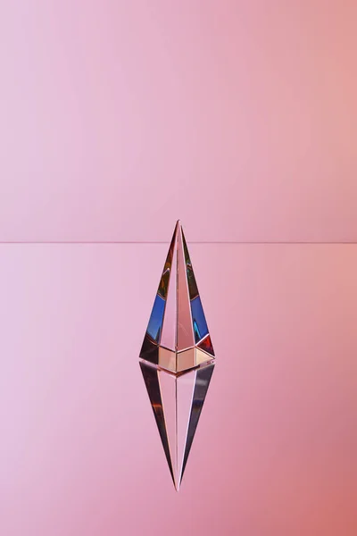 Pirâmide transparente de cristal com reflexão sobre fundo rosa — Fotografia de Stock