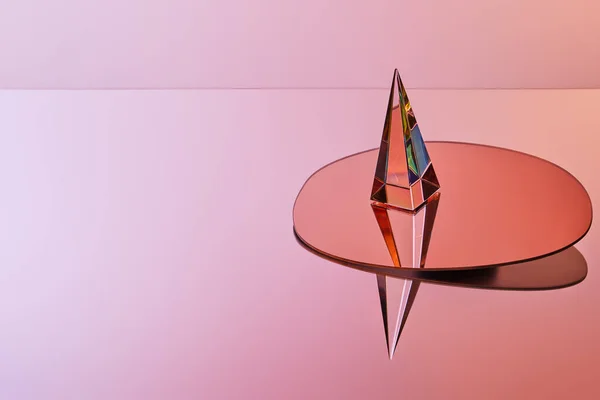 Crystal transparent pyramid with reflection on round mirror on pink background — Stock Photo