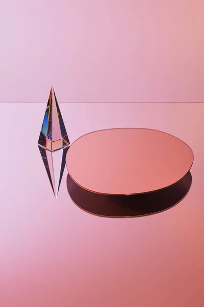 Crystal transparent pyramid with reflection near round mirror on pink background — Stock Photo