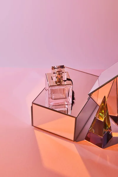 Crystal transparent pyramid near perfume bottle and mirror cubes on pink background — Stock Photo