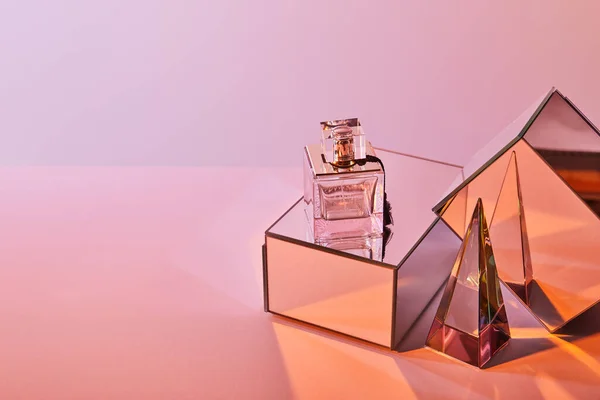 Crystal transparent pyramid near perfume bottle and mirror cubes on pink background — Stock Photo