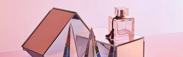 Pirámide transparente de cristal cerca de botella de perfume y cubos de espejo sobre fondo rosa, cultivo panorámico - foto de stock