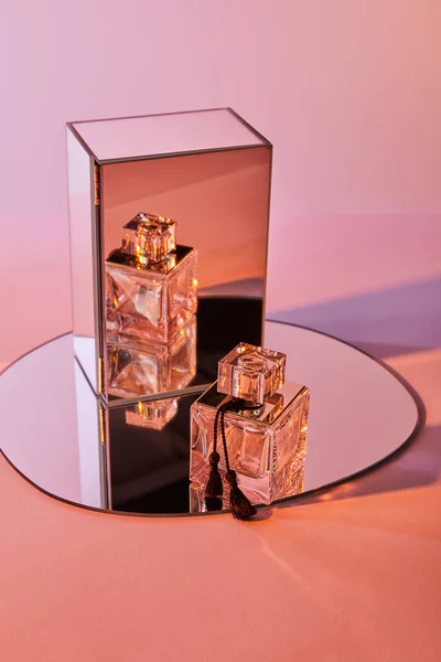 Bottiglia di profumo su specchio rotondo con cubo su sfondo rosa — Foto stock