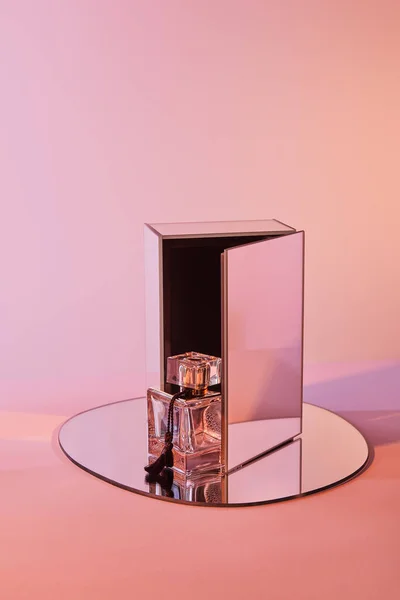 Bottiglia di profumo su specchio rotondo con cubo su sfondo rosa — Foto stock