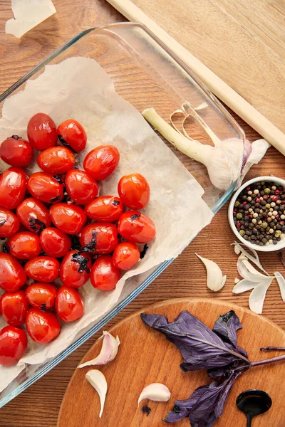 Top view of baking dish with tomatoes near cutting boards with ingredients on wooden background — Stock Photo