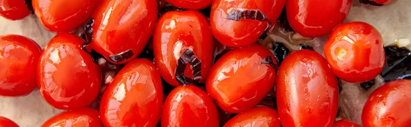 Imagen horizontal de tomates con hojas de albahaca cortadas sobre papel de hornear - foto de stock