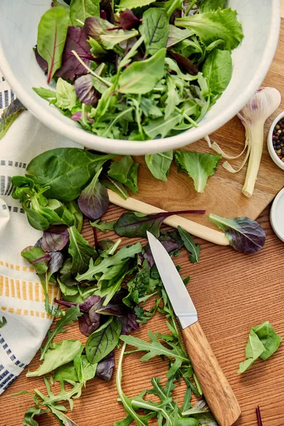 Top view of bowl on cutting board with ingredients near knife and napkin on wooden background — Stock Photo