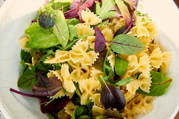 Vista superior de los ingredientes de la ensalada de pasta en tazón blanco - foto de stock