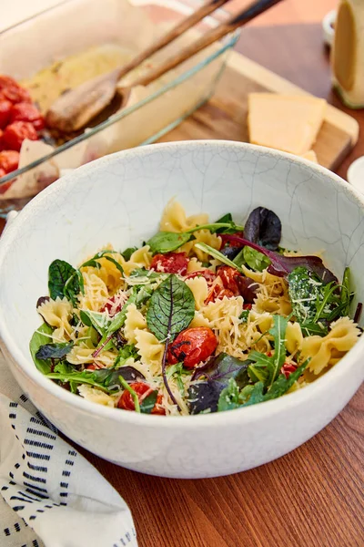 Vue grand angle du bol avec des ingrédients de salade de pâtes près de la serviette sur fond en bois — Photo de stock