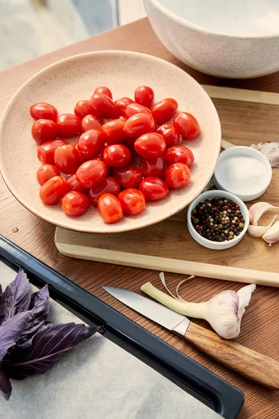 Vista de ángulo alto del tazón cerca de la tabla de cortar y la bandeja del horno con ingredientes en la mesa - foto de stock