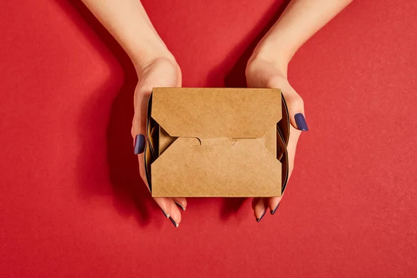 Vista recortada de la mujer sosteniendo caja de cartón para llevar en rojo - foto de stock