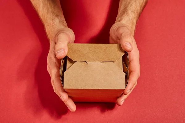 Cropped view of man holding carton takeaway box on red — Stock Photo