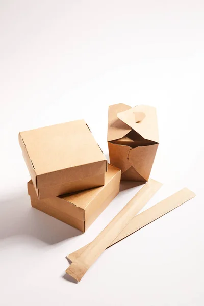 Carton boxes with chinese food and chopsticks in packaging on white — Stock Photo