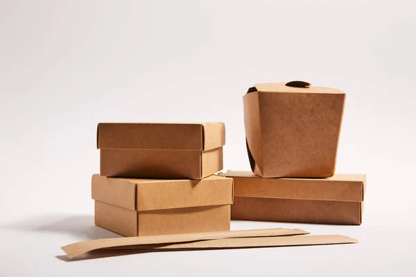 Chopsticks in paper packaging near takeaway boxes with cooked chinese food on white — Stock Photo