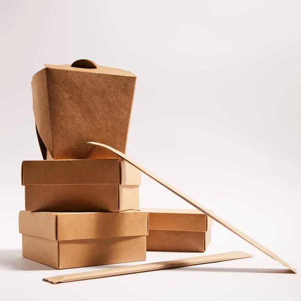 Palillos en el embalaje de papel cerca de cajas de comida para llevar con comida china preparada en blanco — Stock Photo