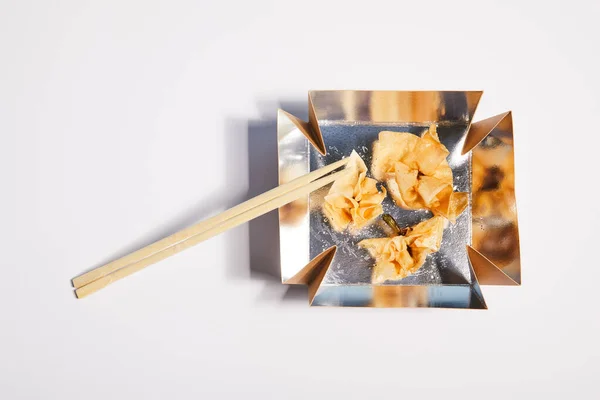 Vista superior de la caja de comida para llevar con albóndigas fritas y palillos en blanco - foto de stock