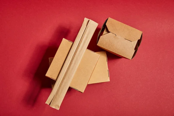 Vista superior de pauzinhos em embalagens de papel perto de caixas de papelão takeaway com comida tradicional chinesa em vermelho — Fotografia de Stock