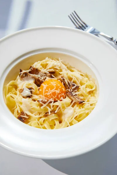 Vista de cerca de la deliciosa pasta carbonara servida con tenedor - foto de stock